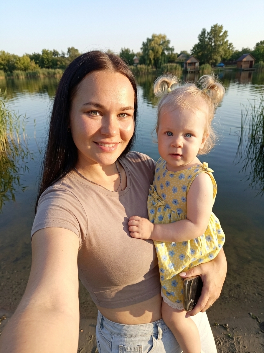 Селфи молодой мамы с дочкой у озера в золотой час Селфи молодой мамы с дочкой у озера в золотой час