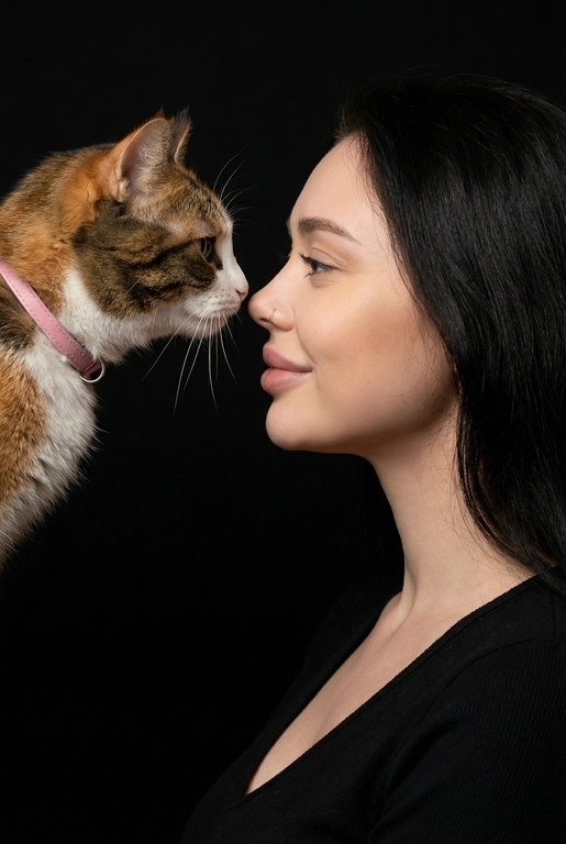 Сделай фото со мной и моим питомцем. Реалистичное фото, с высокой детализацией. Снимок меня и моего питомца в профиль. Фото сделано первым средним планом (Medium CloseUP), в кадре видно часть туловища (с головы до середины груди).
Я стою лицом к своему питомцу в строгий профиль, смотрю прямо на него.
Мой питомец расположен прямо напротив моего лица, также в профиль, смотрит прямо на меня. Наши носы почти соприкасаются. Наши головы могут быть наклонены: например, моя голова наклонена немного вниз, а голова питомца наоборот повыше. Четкая визуальная симметрия между моем лицом и головой моего питомца.
Студийное освещение, мягкий свет, создающий контрастность и скульптурные тени, на самом лице минимум тени. 
 У меня легкая улыбка, питомец смотрит с дружелюбным настроем. Фон черный. 