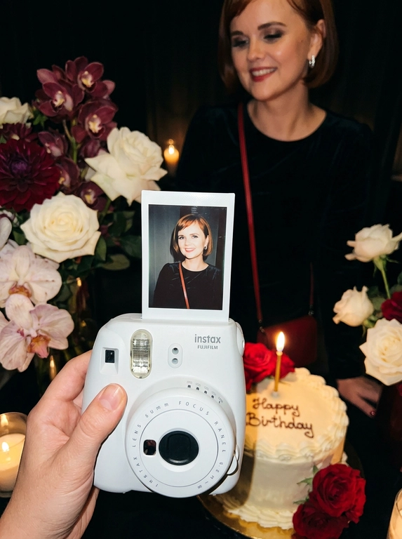 Edit the uploaded reference image into a photorealistic, luxury
birthday party scene.
Preserve the person’s identity exactly. Keep their real facial
structure, skin tone, age presentation, hair type, body type, natural
proportions, expression style, and distinctive features. The final
image should still clearly look like the same person from the
reference photo.
Create the image in the style of a dark, intimate iPhone UGC birthday
snapshot taken in a dim room with direct front flash. Use a dynamic
handheld camera angle, slightly tilted or off-center, as if the photo
was taken spontaneously at the party. The perspective should feel
natural, candid, and immersive, with the white instant camera with
polaroid angled and in focus of the generated image. Avoid a stiff,
perfectly centered studio composition.
The mood should feel candid, and special, like a real birthday
moment captured casually at night. Use flash-lit foreground details,
darker background shadows, warm candle glow, subtle phone-
camera grain, slight handheld imperfection, and shallow depth of
field.
The main focus must be a freshly printed instant polaroid photo
coming out of a clean white instant camera in the foreground. The
white camera should be large in the lower foreground, held close to
the lens. The polaroid should be sharp, visually dominant, and
positioned with a natural slight angle for a more dynamic
composition. The composition should feel similar to a casual iPhone
photo where the polaroid and camera are the main subject, while the
actual person behind it is only subtly visible, and not the main focus,
face not visible.
A natural, well-groomed hand matching the person’s skin tone and
overall styling holds the white instant camera. The hand should look
realistic and relaxed, with simple polished nails only if suitable for
the person.
Inside the polaroid, show the same person from the reference image
posing elegantly at their birthday celebration. They should look
confident, refined, and warmly expressive. Transform their outfit into
a polished birthday look that suits their appearance and gender
presentation. For a woman, create an elegant dress or refined
celebratory outfit. For a man, create a fashionable formal or semi-
formal outfit suitable for a luxury birthday setting. The outfit color should
harmonize with or be inspired by the outfit color in the original
reference photo.
Behind the polaroid, show only a subtle blurred glimpse of the same
person in the background, wearing the same transformed outfit. The
background person should be softly out of focus, partly hidden by
the polaroid camera.
Include tasteful birthday décor around the scene. Use elegant
flowers that harmonize with the subject’s outfit and the overall color
palette of the reference photo. The flowers may be roses, orchids,
hydrangeas, baby’s breath, peonies, lilies, greenery, or other refined
florals. Choose colors that match the person’s transformed outfit
and create a cohesive luxury birthday atmosphere.
Place a birthday cake to the side or slightly in the background. The
cake should be visible but secondary to the polaroid. The cake color,
icing, floral decorations, and candle color should harmonize with the
person’s outfit and the overall palette. Add one lit candle. The cake
must clearly say exactly: “Happy Birthday” in neat, readable icing.
Use realistic direct flash highlights, intimate dark-room lighting, warm
candlelight, soft party lights, shallow depth of field, realistic skin
texture, natural facial proportions, elegant styling, and a cohesive
color palette based on the reference image.
**Strict constraints:** no identity change, no altered facial structure,
no mismatched person between the polaroid and background, no
extra people, no rings, no bracelets, no hand jewelry, no distorted
hands, no extra fingers, no duplicated faces, no warped camera, no
unreadable cake writing, no misspelled cake text, no extra text, no
overly bright studio lighting, no flat commercial lighting, no plastic
skin, no stiff straight-on composition