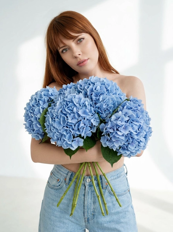 Женщина позирует в на белом фоне. Мягкие тени на стене и полу, ощущение воздуха и пространства. Макияж натуральный: ровный сияющий тон кожи, подчеркнутые ресницы, мягкие розовые губы. Атмосфера кадра — женственность, свежесть, легкость, весеннее настроение. Крупный план по грудь. На ней только светло-голубые широкие джинсы Levi’s с высокой посадкой. Взгляд в камеру, спокойное уверенное выражение лица. Голова немного наклонена вбок.

Какие будут цветы?: Она обнимает большой букет голубых гортензий, полностью прикрывая им грудь. Стебли естественно опущены вниз под весом цветов.