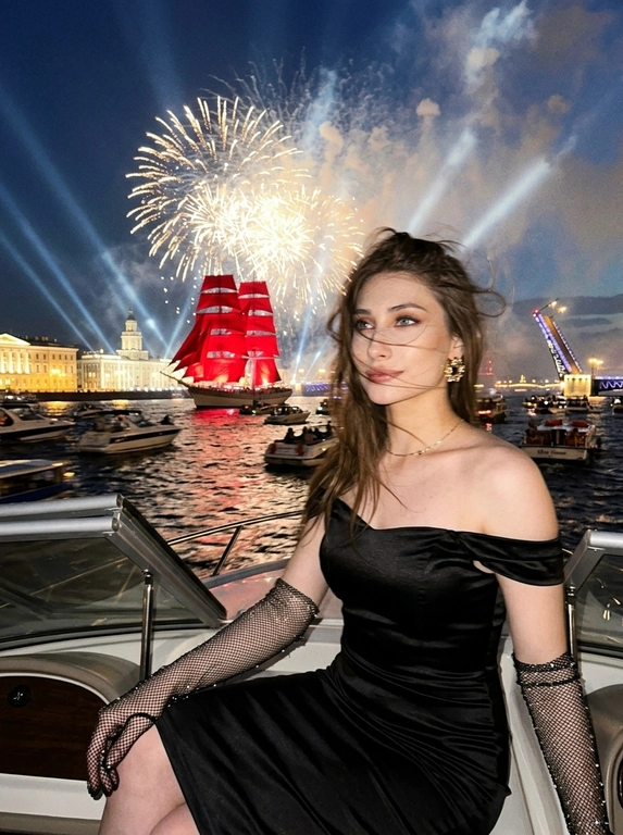 Создай портрет. Ночной экстремально близкий портрет в стиле дорогого fashion-снимка, крупный план, ощущение случайно пойманного момента. Модель, сидящая в энергичной позе на роскошной лодке, плывущей по каналам Санкт-Петербурга во время праздника - "Алые паруса". Волосы развиваются от ветра, слегка на лице. Шикарный вечерний макияж, у нее еле заметная улыбка. 

На заднем плане воды канала, отражающие на горизонте появляются исторические здания, характерные для Санкт-петербурга, рядом с лодкой плывет огромное количество парусных лодок, маленьких яхт, туристических лодок и небольшие лодки вдалеке. Интерьер лодки изысканный. На фоне разводной мост и в центре внимания огромный известный корабль с алыми парусами, паруса подсвечены, с корабля красиво бью прожектора, он в центре внимания, выглядит величественно. Здания подсвечиваются. Все небо залито огромным количеством салютов и фейерверков, а так же светом прожекторов, салюты во весь кадр

Кадр намеренно неидеальный: сильный motion blur, длинная выдержка, высокий ISO, выраженное зерно. Жёсткий контраст, кинематографичная небрежность, ощущение ночи, роскоши и живого, спонтанного кадра. Атмосфера праздника, величественного события. Модель сидит грациозно прямо к кадру, голова повернута в сторону, лицо немного размазано из-за движения, девушка в расфокусе, не смотрит в кадр. Весь фокус на корабле с алыми парусами, они четко подсвечены.

Атласная красная лента "Выпускница 2026"?: Без ленты

Какое будет платье?: Она одета в черное очень приталенное атласное черное платье ниже колена с открытыми плечами, на ней длинные перчатки из сетки со стразами; золотые сверкающие серьги, тонкая золотая цепочка-ожерелье.