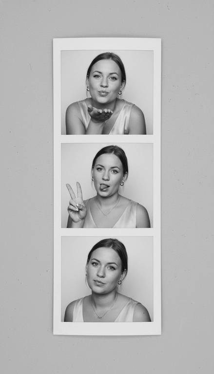  Используя мою фотографию в качестве референса для лица и волос, не изменяя исходные черты лица и сохраняя верность моим физическим характеристикам, создайте ленту из фотографий в ч/б с тремя вертикальными белыми рамками. Лента выглядит так, будто лежит на столе или фоне. Фотографии выглядят профессионально , как будто из настоящей фотобудки. 

В каждой рамке по центру расположены портрет и фотография погрудной проекции одного и того же человека. Взгляд прямо в камеру.

Общая эстетика винтажная, с лёгкой зернистостью и выцветшим качеством, напоминающая классическую аналоговую фотографию. Но при этом изображение выполнено в высоком разрешении. На светло-сером фоне видны едва заметные следы пыли и царапин. Лица человека на белом фоне. 
НЕ ИЗМЕНЯЙТЕ МОЁ ЛИЦО. На верхнем фото девушка посылает зрителю воздушный поцелуй, поднеся правую руку ко рту и слегка поджав губы. Выражение её лица игривое и дружелюбное.  На среднем фото девушка мило и игриво показывает знак мира, высунув язык. Брови слегка приподняты. На нижнем фото девушка позирует, отвернувшись к плечу, смотрит прямо в камеру с более спокойным и уверенным выражением лица. Губы мягко сжаты, взгляд прямой и чувственный. ОДЕЖДА: На ней маленькие серьги-кольца и изящное ожерелье с символом бесконечности поверх светлого атласного или шёлкового топа. На ней естественный макияж, включая глянцевый блеск для губ, лёгкую подводку для глаз и кукольные нарощенные ресницы, без излишеств. У неё квадратный французский маникюр. 
