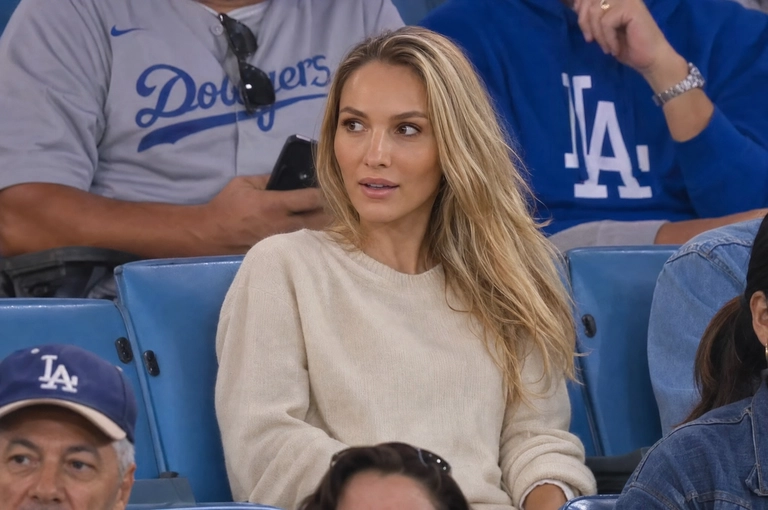 Person sitting in the crowd at a professional baseball game (or it could be any other match that I will write below), filmed from far away by a live broadcast camera. 
Seated in blue stadium chairs, slightly leaned back, looking off to the side with a surprised caught-on-camera expression, lips slightly parted.

Какая будет одежда? : Не менять мою одежду