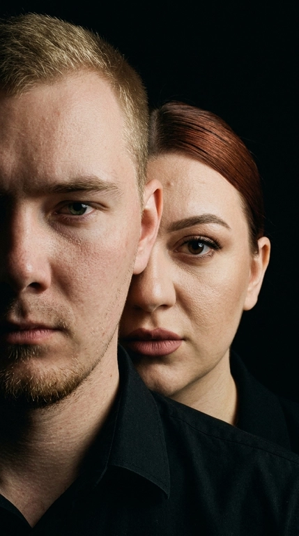 Не менять лицо. Нельзя менять цвет волос. Создайте кинематографическую фотографию. Сохраняйте точную структуру лица, пропорции и естественную асимметрию. Экстремальный портрет крупным планом. У них чёрная одежда. Чёрный фон.
Плотная обрезка: видна только часть лица мужчины (половина лица) Женщина, расположенная прямо за ним. Ее лицо частично скрыто за его головой/плечом Сильная многослойная композиция (мужчина на переднем плане, женщина на заднем плане)
Мужчина, обращенный вперед слегка повернулся сторону. Женщина стоит очень близко позади него.
Женщина стоит очень близко позади него. Губы мягко прижаты или слегка приоткрыты взгляд в камеру. Эмоциональное напряжение вместо романтики. У женщины безупречный легкий скульптурный макияж и матовыми губами пыльная роза. 

Какая будет прическа у женщины?: Её волосы, уложенные в тугой гладкий низкий пучок