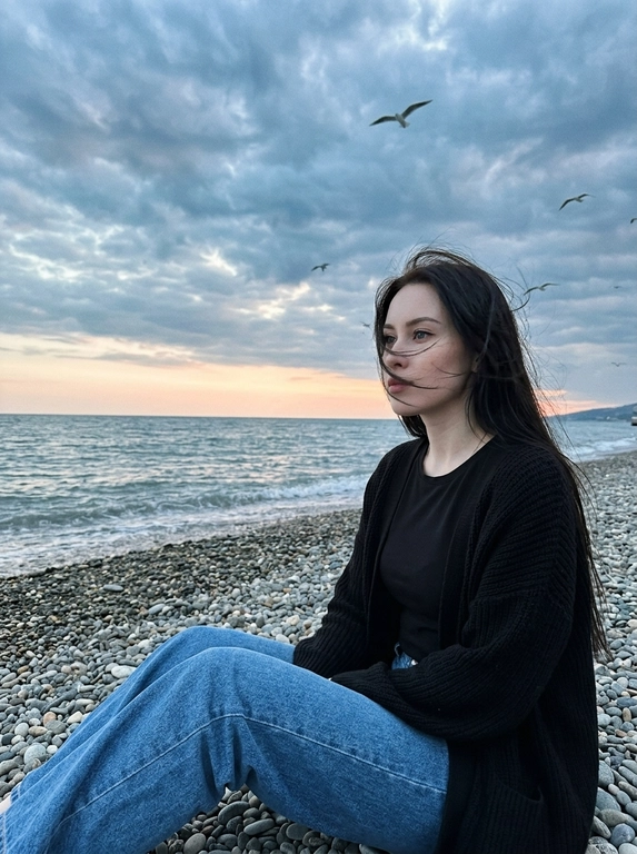 Сохранить внешность 1:1 - лицо, черты, пропорции, возраст, текстуру кожи; фото - единственный эталон. формат 3:4. Атмосферная морская сцена на закате: драматичное облачное небо, холодные голубо-серые оттенки с мягким персиковым у горизонта. Модель сидит боком на гальке у линии прибоя, корпус развернут к морю, взгляд в сторону моря. Ветер растрёпывает волосы, лицо частично перекрыто прядями (волосы развиваются ТОЛЬКО ЕСЛИ они длинные, прическа сохраняется с фото 1:1). в небе летают чайки, часть с лёгким motion blur. Одежда: чёрная базовая футболка, чёрный вязаный кардиган свободной посадки, свободные синие джинсы прямого кроя. Съёмка на винтажную плёночную камеру Kodak, объектив 35mm. Цвет в стиле Kodak Portra 400: матовые тени, мягкий контраст, натуральная цветопередача, лёгкая десатурация, выраженное плёночное зерно. Editorial-композиция, высокий фотореализм, 4K.