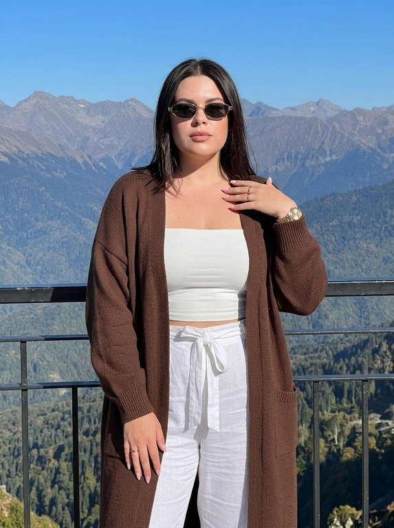 Фотореалистичная fashion-съёмка на природе, ultra realistic, высокая детализация кожи, натуральная текстура пор, реалистичная проработка ткани, профессиональная цветокоррекция, cinematic lighting, высокая резкость, мягкая глубина резкости. Женщина стоит на смотровой площадке в горах, камера расположена фронтально на уровне груди, средний план до бёдер. Композиция вертикальная, модель находится в центре кадра, за её спиной открывается панорамный вид на горные хребты. Поза спокойная и уверенная: корпус направлен к камере, плечи расслаблены, одна рука опущена вдоль тела, другая поднята к плечу, создавая элегантную позу, взгляд направлен в камеру через солнцезащитные очки. Одежда в лёгком casual-luxury стиле: белый спортивный топ-бандо без рукавов, подчёркивающий талию, свободные белые брюки с мягкой тканью и завязками на поясе, сверху лёгкий длинный кардиган или накидка тёплого шоколадно-коричневого оттенка с широкими рукавами. Аксессуары: узкие тёмные солнцезащитные очки с тонкой металлической оправой, на руке золотые часы и аккуратные кольца на пальцах, маникюр светлый розово-нюдовый. Макияж аккуратный и гламурный: ровный тёплый тон кожи, лёгкий бронзер, выразительные брови, длинные ресницы, нюдово-розовые губы с мягким матовым эффектом, кожа выглядит гладкой, естественной и детализированной. Освещение яркое естественное — тёплый солнечный свет падает сбоку и немного спереди, подчёркивает контуры лица и складки одежды, свет создаёт мягкие тени и усиливает глубину пейзажа. Фон — масштабный горный пейзаж с несколькими слоями горных хребтов, покрытых лесом, уходящих в голубую атмосферную дымку, на переднем плане чёрное металлическое ограждение смотровой площадки, небо чистое насыщенно-голубое. Цветовая палитра: глубокий голубой, природные зелёные и серо-синие оттенки гор, белый, тёплый коричневый, чёрный. Контрастная, но натуральная цветокоррекция, высокая фотореалистичность, детализированная кожа, реалистичная текстура ткани и природного ландшафта, стиль современной travel-fashion фотографии.