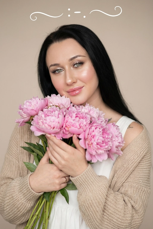 Нежный естественный портрет женщины, смотрящей в камеру и мягко улыбающейся. Она держит большой букет розовых пионов близко к груди. Уютное романтическое настроение. Белое платье, бежевый вязаный кардиган. Эффектный макияж на лице:  бежевые тени с лёгким мерцанием, длинные объемные ресницы, сияющий хайлайтер на скулах и кончике носа, блеск на губах,  легкий розовый румянец, сияющая кожа, нежная женская красота. 

Нейтральный бежевый фон. Мягкий рассеянный дневной свет, малая глубина резкости, кинематографическое боке. Стиль редакционной фотографии, теплая пастельная цветовая палитра, высокая детализация, реалистичная текстура кожи, эффект объектива 85 мм, f/1.8, лайфстайл-фотография. Наверху поверх фото белым красивым рукописным шрифтом с завитками написано:  : -    