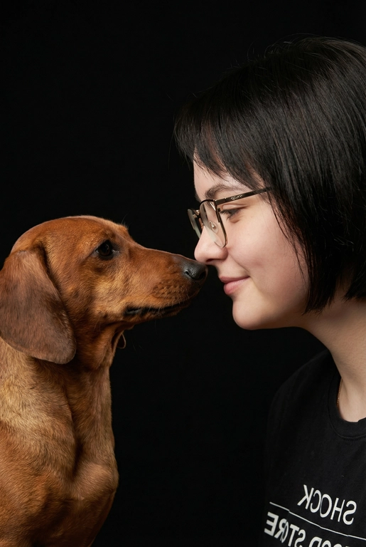 Сделай фото со мной и моим питомцем. Реалистичное фото, с высокой детализацией. Снимок меня и моего питомца в профиль. Фото сделано первым средним планом (Medium CloseUP), в кадре видно часть туловища (с головы до середины груди).
Я стою лицом к своему питомцу в строгий профиль, смотрю прямо на него.
Мой питомец расположен прямо напротив моего лица, также в профиль, смотрит прямо на меня. Наши носы почти соприкасаются. Наши головы могут быть наклонены: например, моя голова наклонена немного вниз, а голова питомца наоборот повыше. Четкая визуальная симметрия между моем лицом и головой моего питомца.
Студийное освещение, мягкий свет, создающий контрастность и скульптурные тени, на самом лице минимум тени. 
 У меня легкая улыбка, питомец смотрит с дружелюбным настроем. Фон черный. 