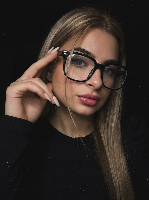 Максимально реалистичная фотография, темная винтажная эстетика в стиле dark glam glasses selfie, атмосферный ночной портрет.
Крупный портрет (Close-Up Portrait), кадр по грудь. Модель делает селфи, телефон не видно. Лицо занимает большую часть кадра, слегка повернуто вполоборота к камере. Голова немного наклонена. Взгляд направлен прямо в объектив, выражение спокойное, уверенное и притягательное. Губы слегка приоткрыты. Одна рука поднята к лицу и аккуратно касается оправы очков, словно поправляя их.
Макияж: Безупречный dark glam makeup. Ровный сияющий тон кожи, четко оформленные темные брови, длинные густые ресницы, тонкая стрелка, мягкий контуринг. Губы розово-винного оттенка с влажным глянцевым финишем.


Аксессуары: Крупные черные очки с прозрачными линзами и массивной квадратной оправой. На линзах заметны мягкие отражения света. Маленькие серьги-гвоздики. Длинный миндалевидный маникюр молочно-бежевого оттенка.

Одежда: Черный лонгслив с глубоким вырезом и небольшими пуговицами спереди. Темная ткань почти сливается с фоном, сохраняя видимую текстуру и силуэт.

Локация: Фон полностью черный.

Освещение: Мягкий приглушенный свет спереди и немного сбоку, словно от экрана телефона. Свет деликатно подсвечивает лицо, очки, губы, пальцы и ногти, оставляя волосы и одежду в глубоких тенях.

Камера: Реалистичное селфи высокого качества, RAW photo, натуральная перспектива смартфона, высокая детализация лица и аксессуаров.

Глубина резкости: Небольшая. Лицо, очки, губы и рука находятся в фокусе, фон растворяется в мягкой темноте.

Кожа: Реалистичная текстура кожи с видимыми порами, естественными переходами света и тени, без эффекта пластика и чрезмерной ретуши.

Детали: Блики на линзах очков, влажный блеск губ, отдельные волоски и пряди на лице, текстура ткани, отражения света на ногтях, легкое пленочное зерно.

Атмосфера: Загадочный ночной вайб, уверенность, женственность, винтажная эстетика, ощущение случайного красивого селфи в темноте.

Какая будет прическа?: Волосы перекинуты на одну сторону. Несколько тонких прядей проходят через щеку и губы, создавая живой эффект движения. Видна естественная текстура и мягкий блеск.