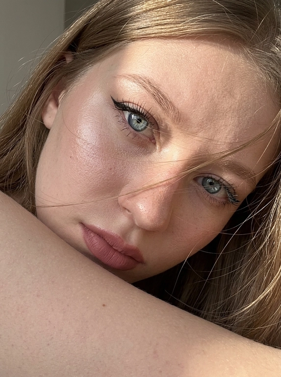 Ультрареалистичная фотография, случайный живой портрет, снятый на iPhone 17 Pro. Эффект настоящего кадра, сделанного в моменте, без постановочности, без фильтров и ретуши.

Внешность полностью сохранена без изменений. Женщина смотрит прямо в камеру. Голова слегка наклонена в сторону и опирается на плечо, плечо частично закрывает лицо. Выражение загадочное, притягательное и естественное.
Волосы активно развеваются ветром, отдельные пряди частично закрывают лицо и глаза, создавая эффект живого случайного кадра. Максимальная детализация отдельных волосков.

Легкий макияж с акцентом на глаза: длинные объемные ресницы, стрелки cat-eye на верхнем веке, идеально оформленные брови. Нюдовая матовая помада оттенка пыльной розы с контуром на тон темнее, влажный хайлайтер на скулах и переносице.

Одежда не видна. Основной акцент на лице, глазах и волосах.

Яркий прямой солнечный свет падает под углом на лицо, интенсивно подсвечивая глаза, подчеркивая глубину радужки, длинные ресницы и естественные блики в глазах. Солнечные лучи создают красивые световые акценты в волосах и на коже.

Естественная текстура кожи с видимыми порами, микрорельефом, легкими несовершенствами, едва заметными капиллярами в глазах. Живая кожа без эффекта пластика. Легкий цифровой шум, характерный для реальной фотографии.

Shot on iPhone 17 Pro, natural light, candid portrait, hyper detailed iris, visible skin pores, realistic skin texture, unedited RAW photo, depth of field, soft highlights, windblown hair, authentic photography, photorealistic, ultra realistic, 8k.