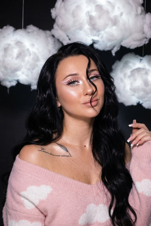 Крупный план лица девушки в стиле «высокой моды». Элегантный макияж глаза с длинными острыми нежно розовые двойные изогнутые стрелки, длинные густые ресницы эффект лучики, нижние густо ресницы накрашены белым и белый каял карандаш на нижнем веке белый Хайлайтер во внутренних уголках и скулах. Губы слегка приоткрыты в легкой ухмылке в легком блеске. Голова наклонена в сторону. На ней пушистый дорогой кашемировый нежно розовый свитер с белыми облаками плечи открыты.
За ней свисают объемные пушистые облака из ваты подсвеченные белым изнутри. Тело и декольте подсвечены хайлайтером и шиммером. Высокая детализация текстур кожи, одежды и волос. Черты лица-полностью сохранены как на референсном фото.
Ногти френч квадрат длинные.
На фоне светлая большая бьюти студия, вокруг темно, ее лицо освещено яркой лампой.  Волосы очень длинные блестящие прическа пляжные локоны. Локон волос падает на лицо 