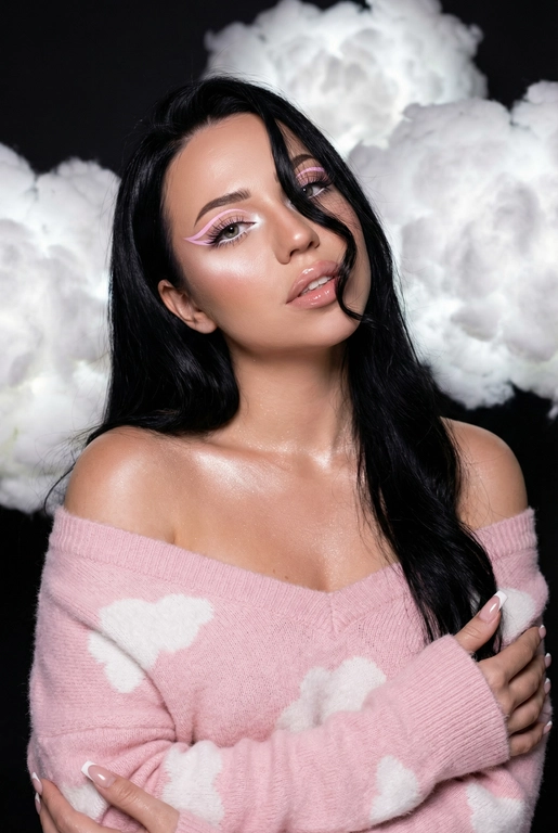 Крупный план лица девушки в стиле «высокой моды». Элегантный макияж глаза с длинными острыми нежно розовые двойные изогнутые стрелки, длинные густые ресницы эффект лучики, нижние густо ресницы накрашены белым и белый каял карандаш на нижнем веке белый Хайлайтер во внутренних уголках и скулах. Губы слегка приоткрыты в легкой ухмылке в легком блеске. Голова наклонена в сторону. На ней пушистый дорогой кашемировый нежно розовый свитер с белыми облаками плечи открыты.
За ней свисают объемные пушистые облака из ваты подсвеченные белым изнутри. Тело и декольте подсвечены хайлайтером и шиммером. Высокая детализация текстур кожи, одежды и волос. Черты лица-полностью сохранены как на референсном фото.
Ногти френч квадрат длинные.
На фоне светлая большая бьюти студия, вокруг темно, ее лицо освещено яркой лампой.  Волосы очень длинные блестящие. Локон волос падает на лицо 