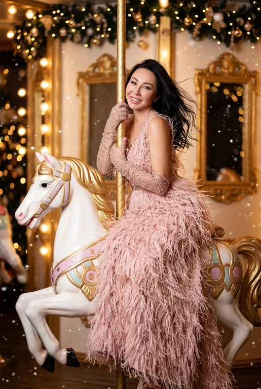 Сказочный праздничный портрет на ретро-карусели, вертикальный кадр до пола. Девушка сидит боком верхом на белой карусельной лошадке с золотыми и пастельно-розовыми декоративными элементами, руками обнимает золотой столб, на ней, уши украшены свисающими серьгами. Волосы распущены и развеваются, лицо слегка повернуто в сторону, выражение расслабленное и радостное. Фон залит тёплым светом гирлянд и лампочек карусели, золотые рамы зеркал и размытые огни парка создают атмосферу роскошной рождественской ярмарки, в воздухе лёгкие снежинки и боке. Гламурный праздничный стиль, насыщенные тёплые тона, мягкое боке, high fashion editorial, 8k, cinematic lighting, shallow depth of field, festive atmosphere. --ar 9:16 --v 6 --style raw --q 2

На ней пышное вечернее платье нежно‑пудрового цвета, полностью покрытое длинными перьями, создающими объём и движение, на руках блестящие длинные перчатки