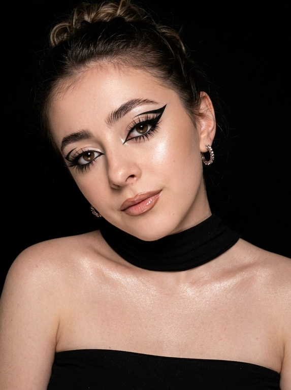 Крупный план лица женщины в стиле «высокой моды». Элегантный макияж: глаза с длинными острыми чёрными стрелками, длинные густые ресницы с эффектом «лучики», нижние ресницы также прокрашены. Хайлайтер во внутренних уголках глаз и на скулах. Губы слегка приоткрыты в лёгкой ухмылке, с лёгким блеском и светло-коричневым карандашом по контуру. Голова наклонена в сторону,  На ней чёрный топ из тканевого материала без бретелек. Тело и зона декольте подсвечены хайлайтером, на шее чёрная ткань. Высокая детализация текстур кожи, одежды и волос. Черты лица полностью сохранены, как на референсном фото. Фон чёрный, студийный, вокруг темнота, лицо освещено яркой лампой. 8K, тёмный минималистичный фон без лишних деталей. Гиперреализм, добавить зерно.

Какая будет прическа?: Волосы уложены в небрежный пучок.