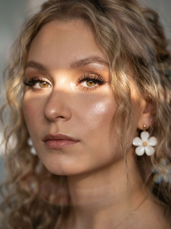 Кинематографический эффект с добавлением зерна. Ультрареалистичный, экстремально крупный портрет части лица девушки: на неё падает солнечный свет полосой, освещая глаза; её голова немного повёрнута в сторону. Тело подсвечено хайлайтером. Макияж лёгкий, с насыщенным хайлайтером; ресницы длинные, пышные. Она смотрит в камеру со спокойным, созерцательным выражением. Освещение мягкое, с лёгким акцентом на её лицо, создаёт нежные тени и подчёркивает черты. В ушах — серьги в виде белых цветов. Фон минималистичный и нейтральный, что усиливает спокойную и элегантную атмосферу. Фото смазанное, как будто сделано в движении, с двойной экспозицией.


Какая будет прическа?: Волосы кудрявые, частично падают на лицо.