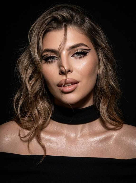 Крупный план лица женщины в стиле «высокой моды». Элегантный макияж: глаза с длинными острыми чёрными стрелками, длинные густые ресницы с эффектом «лучики», нижние ресницы также прокрашены. Хайлайтер во внутренних уголках глаз и на скулах. Губы слегка приоткрыты в лёгкой ухмылке, с лёгким блеском и светло-коричневым карандашом по контуру. Голова наклонена в сторону,  На ней чёрный топ из тканевого материала без бретелек. Тело и зона декольте подсвечены хайлайтером, на шее чёрная ткань. Высокая детализация текстур кожи, одежды и волос. Черты лица полностью сохранены, как на референсном фото. Фон чёрный, студийный, вокруг темнота, лицо освещено яркой лампой. 8K, тёмный минималистичный фон без лишних деталей. Гиперреализм, добавить зерно.

Какая будет прическа?: Волосы густые уложены в пляжные локоны, локон волос падает на лицо.