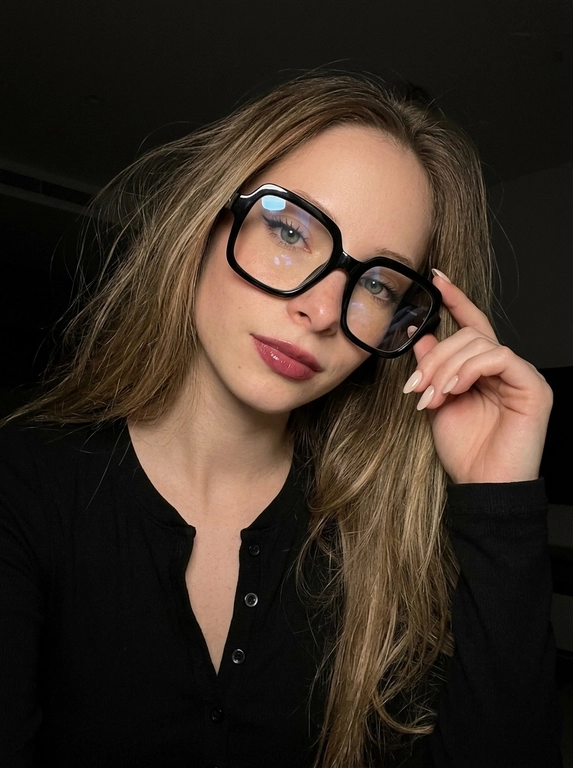 Максимально реалистичная фотография, темная винтажная эстетика в стиле dark glam glasses selfie, атмосферный ночной портрет.
Крупный портрет (Close-Up Portrait), кадр по грудь. Модель делает селфи, телефон не видно. Лицо занимает большую часть кадра, слегка повернуто вполоборота к камере. Голова немного наклонена. Взгляд направлен прямо в объектив, выражение спокойное, уверенное и притягательное. Губы слегка приоткрыты. Одна рука поднята к лицу и аккуратно касается оправы очков, словно поправляя их.
Макияж: Безупречный dark glam makeup. Ровный сияющий тон кожи, четко оформленные темные брови, длинные густые ресницы, тонкая стрелка, мягкий контуринг. Губы розово-винного оттенка с влажным глянцевым финишем.


Аксессуары: Крупные черные очки с прозрачными линзами и массивной квадратной оправой. На линзах заметны мягкие отражения света. Маленькие серьги-гвоздики. Длинный миндалевидный маникюр молочно-бежевого оттенка.

Одежда: Черный лонгслив с глубоким вырезом и небольшими пуговицами спереди. Темная ткань почти сливается с фоном, сохраняя видимую текстуру и силуэт.

Локация: Фон полностью черный.

Освещение: Мягкий приглушенный свет спереди и немного сбоку, словно от экрана телефона. Свет деликатно подсвечивает лицо, очки, губы, пальцы и ногти, оставляя волосы и одежду в глубоких тенях.

Камера: Реалистичное селфи высокого качества, RAW photo, натуральная перспектива смартфона, высокая детализация лица и аксессуаров.

Глубина резкости: Небольшая. Лицо, очки, губы и рука находятся в фокусе, фон растворяется в мягкой темноте.

Кожа: Реалистичная текстура кожи с видимыми порами, естественными переходами света и тени, без эффекта пластика и чрезмерной ретуши.

Детали: Блики на линзах очков, влажный блеск губ, отдельные волоски и пряди на лице, текстура ткани, отражения света на ногтях, легкое пленочное зерно.

Атмосфера: Загадочный ночной вайб, уверенность, женственность, винтажная эстетика, ощущение случайного красивого селфи в темноте.

Какая будет прическа?: Волосы выглядят естественно и растрёпанно, с мягкой текстурой и свободными прядями у лица. Создаёт эффект живого, случайного и стильного кадра, без ощущения идеальной салонной укладки.