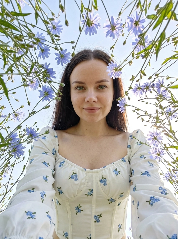 Создай портрет, не меняя черты лица. Экстремальный нижний ракурс (взгляд «из травы»), направленный вертикально вверх на женщину. Цветы тянутся к центру, свет проходит сквозь лепестки (эффект подповерхностного рассеивания). Женщина в белом корсетном топе с длинными рукавами-фонариками и открытыми плечами. Весь корсетный топ — в мелких голубых цветочках. На лице нежная улыбка. Акцент на деталях и коже: кожа детализированная. ISO 100 для отсутствия шумов, выдержка 1/2000 сек. Стиль National Geographic, мода. Гиперреализм, разрешение 8K.


Какие будут цветы?: Она окружена луговыми полевыми голубыми цветами — видны зелёные стебли. голубого цвета, слегка напоминают маки.