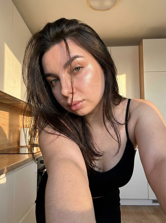   
Создай фото не меняя черты лица Волосы блестящие часть
прядей волос небрежно падает на лицо
что создает загадочный и слегка дерзкий эффект.
На щеках теле и в уголках глаз хайлайтер
Губы накрашены лёгким блеском На ней надет чёрный топик на тонких лямках.
Девушка слегка наклонилась к камере, одна её рука вытянута вперед (что характерно для селфи), создавая ощущение близости к зрителю.
Свет мягкий, теплый, направленный сверху
Сбоку светит солнечный свет
На фоне светлая кухня
Высокая детализация текстур кожи и волос.