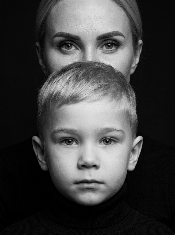 Сохрани реалистичную текстуру кожи и пор, избегая пластического сглаживания.
Сохрани естественные пропорции.
Друг за другом.
Создай портрет крупным планом, не изменяя черт лица.
Перенеси изображение точно так, как это показано на прилагаемых фотографиях.
Черно-белый, выразительный студийный портрет крупным планом, сфокусированный на лицах Взрослого человека и ребенка.
Взрослый стоит на заднем плане, его рот закрывает полностью голова ребенка, видны только глаза и лоб.
Ребенок на переднем плане, смотрит прямо в камеру с важным выражением лица. Он одет в черную водолазку с горлом.
Фон темный.
Освещение мягкое, но эффектное, с
акцентом только на чертах лица, расположение высокое, а объект съемки кинематографичный.
Внешность и черты лица строго сохранены по сравнению с эталонной фотографией.