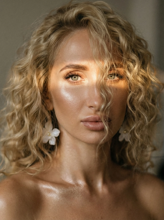 Кинематографический эффект с добавлением зерна. Ультрареалистичный, экстремально крупный портрет части лица девушки: на неё падает солнечный свет полосой, освещая глаза; её голова немного повёрнута в сторону. Тело подсвечено хайлайтером. Макияж лёгкий, с насыщенным хайлайтером; ресницы длинные, пышные. Она смотрит в камеру со спокойным, созерцательным выражением. Освещение мягкое, с лёгким акцентом на её лицо, создаёт нежные тени и подчёркивает черты. В ушах — серьги в виде белых цветов. Фон минималистичный и нейтральный, что усиливает спокойную и элегантную атмосферу. Фото смазанное, как будто сделано в движении, с двойной экспозицией.


Какая будет прическа?: Волосы кудрявые, частично падают на лицо.