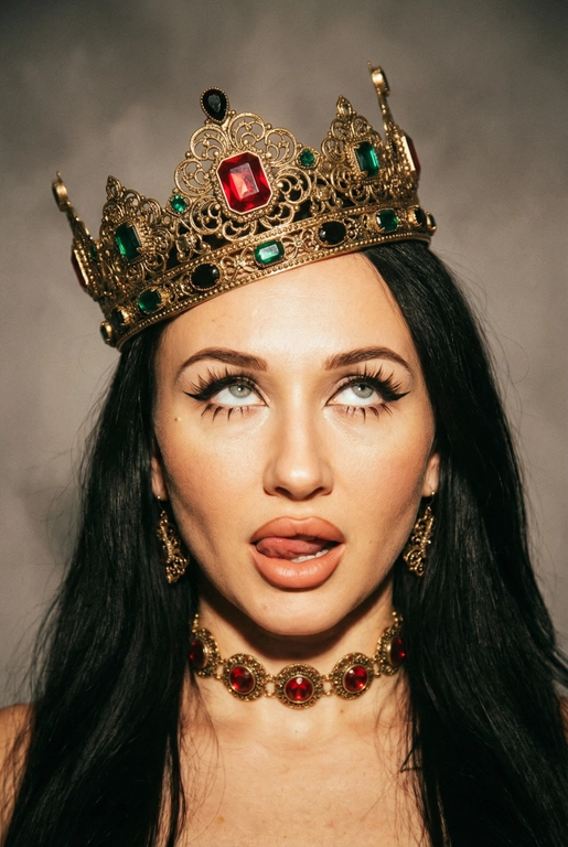 Создай фото -детальное описание художественного портрета девушки, выполненного в популярной современной эстетике, сочетающей элементы «е-qirl» и стиля «rebellious royalty» (бунтарская королевская особа).
:Центральный образ и внешность:
• Лицо и поза: Девушка позирует в дерзкой и провокационной манере.
Её глаза закатаны (или направлены сильно в сторону и вверх), а кончик языка слегка высунут. Это создает образ, сочетающий в себе игривость, бунт и некоторую отрешенность.
Элегантный макияж глаза с длинными острыми черными стрелками, длинные густые ресницы эффект лучики, нижние ресницы накрашены, хайлайтер во внутренних уголках и скулах.
Пухлые полностью прокрашенные телесной матовые губы слегка приоткрыты легкий блеск и светло-коричневый карандаш по краям. персиково-розового оттенка.
Не меняй мою прическу. 
Корона: На голове массивная высокая корона в винтажном стиле. Она украшена сложным филигранным узором и крупными драгоценными камнями: по центру расположен большой квадратный красный камень (рубин), по бокам - камни зеленого (изумруд) и черного цветов. Корона сидит немного небрежно, подчеркивая неформальность образа.
Ожерелья:
На шее надет чокер, выполненный в одном стиле с короной - цепочка с круглыми красными камнями в оправе. В ушах серьги по такому же типо как корона •
Фон: Нейтральный, дымчато-серый или слегка туманный. Он лишен деталей, что позволяет полностью сфокусировать внимание на ярких аксессуарах и лице модели.
Освещение и обработка: Свет мягкий, рассеянный. Фотография имеет характерную обработку с эффектом «зернистости» (пленочное зерно), что придает ей винтажный и художественный вид.
Цветовая гамма теплая, с акцентом на золото и красный цвет.
Общее впечатление:
Снимок транслирует идею современной интерпретации власти и красоты. Это противопоставление классического символа величия (короны) и современного неформального поведения.
Образ выглядит стильно и кинематографично и запоминающе, сильная вспышка. Корона цвета золота.