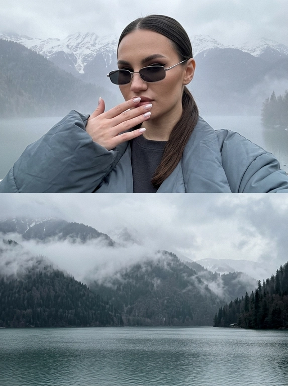 Реалистичный фотоколлаж из двух фотографий, снятых на iPhone. Верхняя и нижняя часть выглядят как две отдельные настоящие фотографии, соединённые в один цельный кадр. Холодная приглушённая цветокоррекция, лёгкая зернистость, немного затемнённая экспозиция, натуральное RAW-качество.

ВЕРХНЯЯ ФОТОГРАФИЯ — женщина: крупный портрет на фоне холодного горного пейзажа. На ней объёмная oversize-куртка холодного серо-синего оттенка, широкие рукава и массивный силуэт, под ней тёмно-серый топ. 

Макияж выразительный: сияющая естественная кожа с реальной текстурой, высокие выразительные скулы с глубоким контурированием, аккуратные брови, острая удлинённая восточная стрелка, губы с влажным глянцевым блеском.

Рот закрыт. Одна рука красиво поднята к лицу, ладонь мягко прикрывает нижнюю часть лица, пальцы расслаблены и естественно расположены. Ногти тонкие, аккуратной формы, сатиново-молочного оттенка с мягким жемчужным переливом и несколькими маленькими стильными стразами.

НИЖНЯЯ ФОТОГРАФИЯ — отдельный пейзаж без женщины: огромное холодное горное озеро с лёгкой рябью на воде, серо-бирюзовая холодная вода, на заднем плане массивные горы, полностью покрытые густым тёмным лесом. Между горами плотный бело-серый туман, который мягко окутывает лес и частично скрывает вершины. Пасмурное холодное небо, влажная атмосферная дымка, дальние горы растворяются в тумане. Очень глубокая перспектива и ощущение огромного пространства.

Весь коллаж должен выглядеть как две реальные фотографии из одного путешествия: холодный воздух, естественный свет, реалистичная вода, лес, туман и горы, лёгкое цифровое зерно, натуральная детализация, без CGI, HDR, пластиковой кожи и чрезмерной обработки.

Причёска: Волосы аккуратно зачёсаны назад и собраны в гладкий низкий хвост у основания шеи. У корней укладка ровная и блестящая, без пушистости и выбивающихся прядей. Образ выглядит минималистично и современно.

Очки: Узкие прямоугольные солнцезащитные очки с тонкой светлой металлической оправой и тёмными линзами.