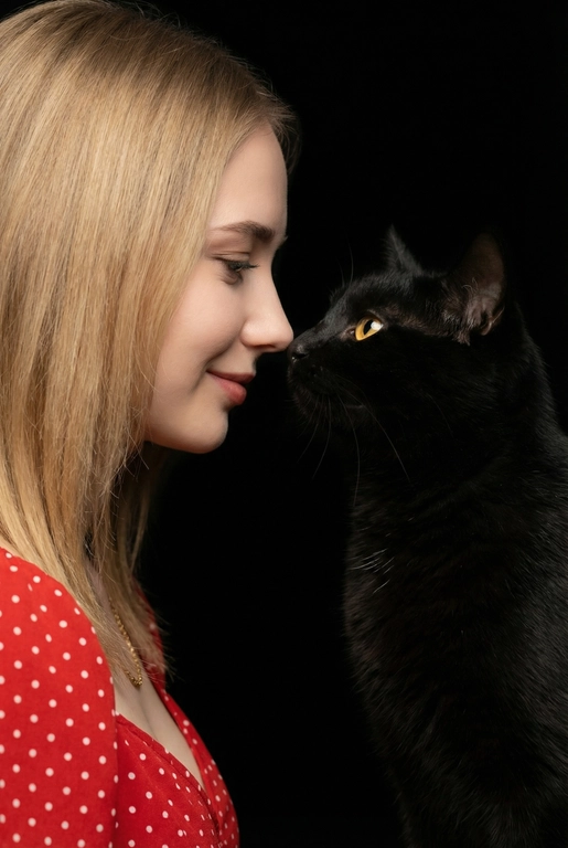 Сделай фото со мной и моим питомцем. Реалистичное фото, с высокой детализацией. Снимок меня и моего питомца в профиль. Фото сделано первым средним планом (Medium CloseUP), в кадре видно часть туловища (с головы до середины груди).
Я стою лицом к своему питомцу в строгий профиль, смотрю прямо на него.
Мой питомец расположен прямо напротив моего лица, также в профиль, смотрит прямо на меня. Наши носы почти соприкасаются. Наши головы могут быть наклонены: например, моя голова наклонена немного вниз, а голова питомца наоборот повыше. Четкая визуальная симметрия между моем лицом и головой моего питомца.
Студийное освещение, мягкий свет, создающий контрастность и скульптурные тени, на самом лице минимум тени. 
 У меня легкая улыбка, питомец смотрит с дружелюбным настроем. Фон черный. 