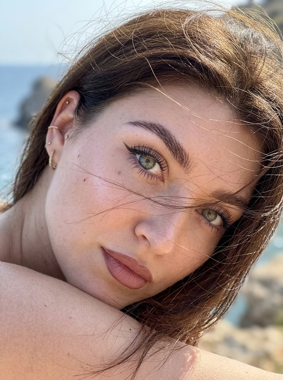 Ультрареалистичная фотография, случайный живой портрет, снятый на iPhone 17 Pro. Эффект настоящего кадра, сделанного в моменте, без постановочности, без фильтров и ретуши.

Внешность полностью сохранена без изменений. Женщина смотрит прямо в камеру. Голова слегка наклонена в сторону и опирается на плечо, плечо частично закрывает лицо. Выражение загадочное, притягательное и естественное.
Волосы активно развеваются ветром, отдельные пряди частично закрывают лицо и глаза, создавая эффект живого случайного кадра. Максимальная детализация отдельных волосков.

Легкий макияж с акцентом на глаза: длинные объемные ресницы, стрелки cat-eye на верхнем веке, идеально оформленные брови. Нюдовая матовая помада оттенка пыльной розы с контуром на тон темнее, влажный хайлайтер на скулах и переносице.

Одежда не видна. Основной акцент на лице, глазах и волосах.

Яркий прямой солнечный свет падает под углом на лицо, интенсивно подсвечивая глаза, подчеркивая глубину радужки, длинные ресницы и естественные блики в глазах. Солнечные лучи создают красивые световые акценты в волосах и на коже.

Естественная текстура кожи с видимыми порами, микрорельефом, легкими несовершенствами, едва заметными капиллярами в глазах. Живая кожа без эффекта пластика. Легкий цифровой шум, характерный для реальной фотографии.

Shot on iPhone 17 Pro, natural light, candid portrait, hyper detailed iris, visible skin pores, realistic skin texture, unedited RAW photo, depth of field, soft highlights, windblown hair, authentic photography, photorealistic, ultra realistic, 8k.