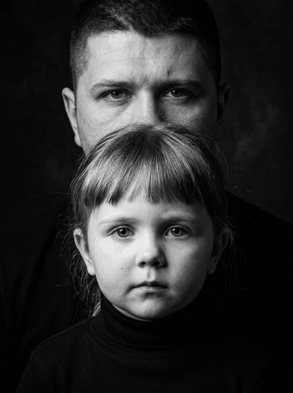 Сохрани реалистичную текстуру кожи и пор, избегая пластического сглаживания.
Сохрани естественные пропорции.
Друг за другом.
Создай портрет крупным планом, не изменяя черт лица.
Перенеси изображение точно так, как это показано на прилагаемых фотографиях.
Черно-белый, выразительный студийный портрет крупным планом, сфокусированный на лицах Взрослого человека и ребенка.
Взрослый стоит на заднем плане, его рот закрывает полностью голова ребенка, видны только глаза и лоб.
Ребенок на переднем плане, смотрит прямо в камеру с важным выражением лица. Он одет в черную водолазку с горлом.
Фон темный.
Освещение мягкое, но эффектное, с
акцентом только на чертах лица, расположение высокое, а объект съемки кинематографичный.
Внешность и черты лица строго сохранены по сравнению с эталонной фотографией.