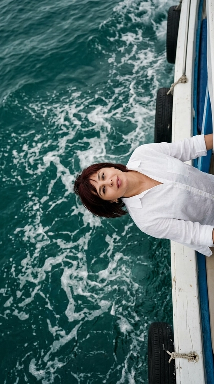 Use attached scheme as a layout reference. Top-down aerial shot, cinematic editorial photo. A character leans back over the white wooden edge of a boat, head tilted back toward deep teal sea water churning with white foam below. The character wears an oversized white linen shirt. Calm, dreamy expression, lips slightly parted, eyes looking up at the camera. The boat has a blue painted trim along the hull and black rubber tire fenders hanging on the side. Turquoise-emerald water fills most of the frame, with swirling foam patterns and soft ripples. Natural overcast daylight, soft diffused lighting, muted cinematic color grading with teal and warm skin tones, shallow depth of field on the water, high detail, photorealistic, shot on 35mm lens from directly above.

Доп. характеристики: цвет волос и прическу не менять