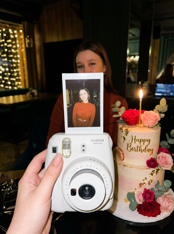 Edit the uploaded reference image into a photorealistic, luxury
birthday party scene.
Preserve the person’s identity exactly. Keep their real facial
structure, skin tone, age presentation, hair type, body type, natural
proportions, expression style, and distinctive features. The final
image should still clearly look like the same person from the
reference photo.
Create the image in the style of a dark, intimate iPhone UGC birthday
snapshot taken in a dim room with direct front flash. Use a dynamic
handheld camera angle, slightly tilted or off-center, as if the photo
was taken spontaneously at the party. The perspective should feel
natural, candid, and immersive, with the white instant camera with
polaroid angled and in focus of the generated image. Avoid a stiff,
perfectly centered studio composition.
The mood should feel candid, and special, like a real birthday
moment captured casually at night. Use flash-lit foreground details,
darker background shadows, warm candle glow, subtle phone-
camera grain, slight handheld imperfection, and shallow depth of
field.
The main focus must be a freshly printed instant polaroid photo
coming out of a clean white instant camera in the foreground. The
white camera should be large in the lower foreground, held close to
the lens. The polaroid should be sharp, visually dominant, and
positioned with a natural slight angle for a more dynamic
composition. The composition should feel similar to a casual iPhone
photo where the polaroid and camera are the main subject, while the
actual person behind it is only subtly visible, and not the main focus,
face not visible.
A natural, well-groomed hand matching the person’s skin tone and
overall styling holds the white instant camera. The hand should look
realistic and relaxed, with simple polished nails only if suitable for
the person.
Inside the polaroid, show the same person from the reference image
posing elegantly at their birthday celebration. They should look
confident, refined, and warmly expressive. Transform their outfit into
a polished birthday look that suits their appearance and gender
presentation. For a woman, create an elegant dress or refined
celebratory outfit. For a man, create a fashionable formal or semi-
formal outfit suitable for a luxury birthday setting. The outfit color should
harmonize with or be inspired by the outfit color in the original
reference photo.
Behind the polaroid, show only a subtle blurred glimpse of the same
person in the background, wearing the same transformed outfit. The
background person should be softly out of focus, partly hidden by
the polaroid camera.
Include tasteful birthday décor around the scene. Use elegant
flowers that harmonize with the subject’s outfit and the overall color
palette of the reference photo. The flowers may be roses, orchids,
hydrangeas, baby’s breath, peonies, lilies, greenery, or other refined
florals. Choose colors that match the person’s transformed outfit
and create a cohesive luxury birthday atmosphere.
Place a birthday cake to the side or slightly in the background. The
cake should be visible but secondary to the polaroid. The cake color,
icing, floral decorations, and candle color should harmonize with the
person’s outfit and the overall palette. Add one lit candle. The cake
must clearly say exactly: “Happy Birthday” in neat, readable icing.
Use realistic direct flash highlights, intimate dark-room lighting, warm
candlelight, soft party lights, shallow depth of field, realistic skin
texture, natural facial proportions, elegant styling, and a cohesive
color palette based on the reference image.
**Strict constraints:** no identity change, no altered facial structure,
no mismatched person between the polaroid and background, no
extra people, no rings, no bracelets, no hand jewelry, no distorted
hands, no extra fingers, no duplicated faces, no warped camera, no
unreadable cake writing, no misspelled cake text, no extra text, no
overly bright studio lighting, no flat commercial lighting, no plastic
skin, no stiff straight-on composition
