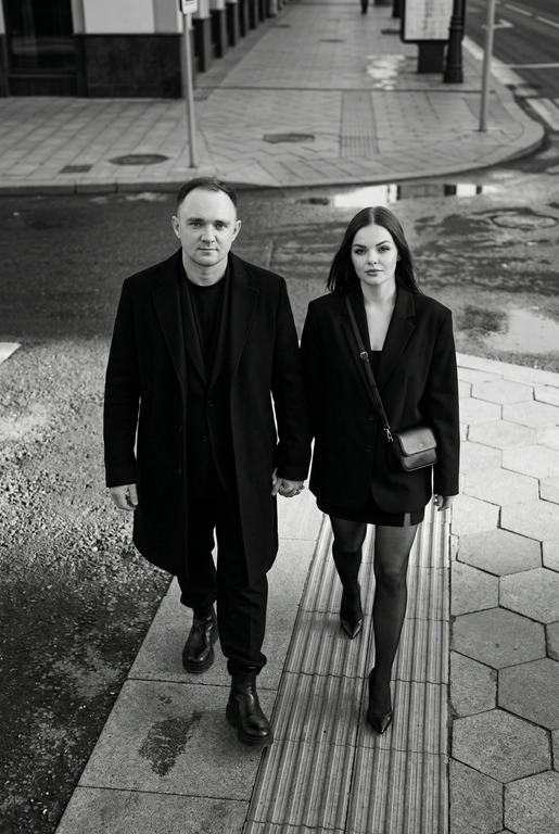 Черно-белая художественная фотография, ультрареализм, 8K, профессиональная съёмка; (оба): в кадре мужчина и женщина; каждый персонаж жёстко привязан к своему загруженному референсу, лица используются напрямую, без генерации, усреднения, подмены или смешения. Вид сверху под углом. Они идут по городской улице, держась за руки; шаг в движении, эффект «пойманного кадра». Смотрим вверх в камеру, выражение спокойное, уверенное, отстранённое.
Полностью чёрные образы modern classic: женщина — оверсайз-пиджак, короткое платье/юбка, плотные колготки, остроносые каблуки, маленькая сумка; мужчина — длинное пальто, свободный костюм, массивные ботинки.
Фон: асфальт, плитка, тактильная дорожка, геометрия.
Контрастный свет, мягкие тени, высокая детализация тканей.
Стиль: black & white, cinematic, high fashion, editorial, minimalism, street photography.
Качество: ultra high resolution, sharp focus, film grain, без ретуши.
