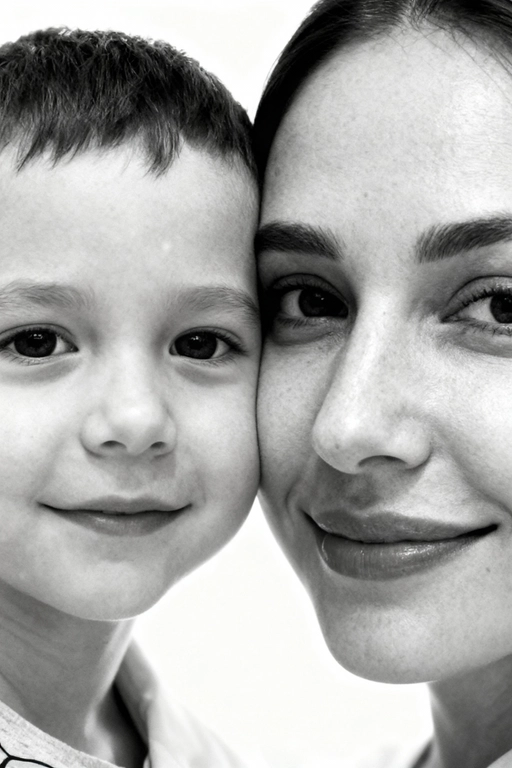 Сверхреалистичная черно-белая художественная фотография 8K женщины и ребенка, снятая очень крупным планом, щека к щеке так что видны только правая половина лица женщины и левая половина лица ребенка. которые смотрят в камеру. Их лица расположены рядом, почти соприкасаясь, образуя идеально сбалансированную симметричную композицию. Каждая деталь передана с фотографической точностью: тонкая текстура кожи и плавные градиенты света и тени. Видимая половина женщины включает ее бровь, один глаз , часть ее носа, щеку и губы, слегка приоткрытые в нежной, естественной улыбке, Видимая половина ребенка включает один глаз , круглую мягкую щеку, часть носа и небольшую улыбку, Фон белый и слегка размытый, что подчеркивает эмоциональную близость между ними. Освещение мягкое и рассеянное, создает деликатный контраст и тональную глубину. На снимке запечатлены нежность, близость и связь между матерью и ребенком, запечатленные с потрясающей реалистичностью. Не меняй черты лиц. 