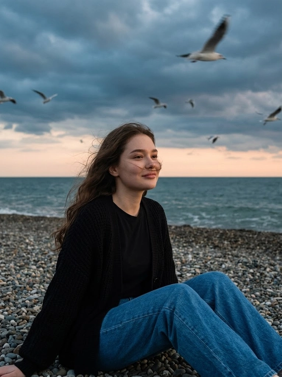 Сохранить внешность 1:1 - лицо, черты, пропорции, возраст, текстуру кожи; фото - единственный эталон. формат 3:4. Атмосферная морская сцена на закате: драматичное облачное небо, холодные голубо-серые оттенки с мягким персиковым у горизонта. Модель сидит боком на гальке у линии прибоя, корпус развернут к морю, взгляд в сторону моря. Ветер растрёпывает волосы, лицо частично перекрыто прядями (волосы развиваются ТОЛЬКО ЕСЛИ они длинные, прическа сохраняется с фото 1:1). в небе летают чайки, часть с лёгким motion blur. Одежда: чёрная базовая футболка, чёрный вязаный кардиган свободной посадки, свободные синие джинсы прямого кроя. Съёмка на винтажную плёночную камеру Kodak, объектив 35mm. Цвет в стиле Kodak Portra 400: матовые тени, мягкий контраст, натуральная цветопередача, лёгкая десатурация, выраженное плёночное зерно. Editorial-композиция, высокий фотореализм, 4K.