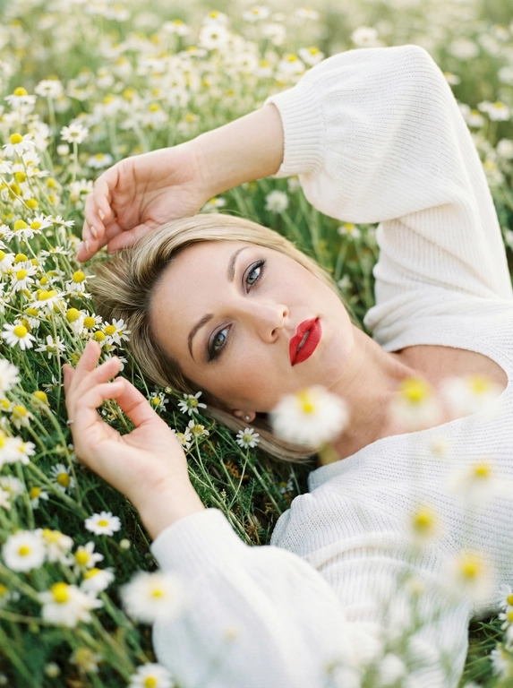Экстремально крупный, кинематографичный портрет лица человека, лежащего среди густых полевых цветов, камера максимально близко — в кадре преимущественно лицо, черты сохранены без изменений, вокруг море цветов, создающее ощущение мягкого природного кокона, одна рука изящно поднята над головой, вторая мягко касается цветов рядом, на переднем плане сбоку частично размытые, не в фокусе цветы добавляют глубину и лёгкое ощущение движения, одета в летнее белое вязаное платье с объёмными рукавами, мягкая текстура ткани едва читается, естественный мягкий свет подчёркивает кожу и блики в волосах, малая глубина резкости, художественное боке, атмосферный кадр с деликатным плёночным зерном.



Какие будут цветы?: Лежит среди густых полевых ромашек