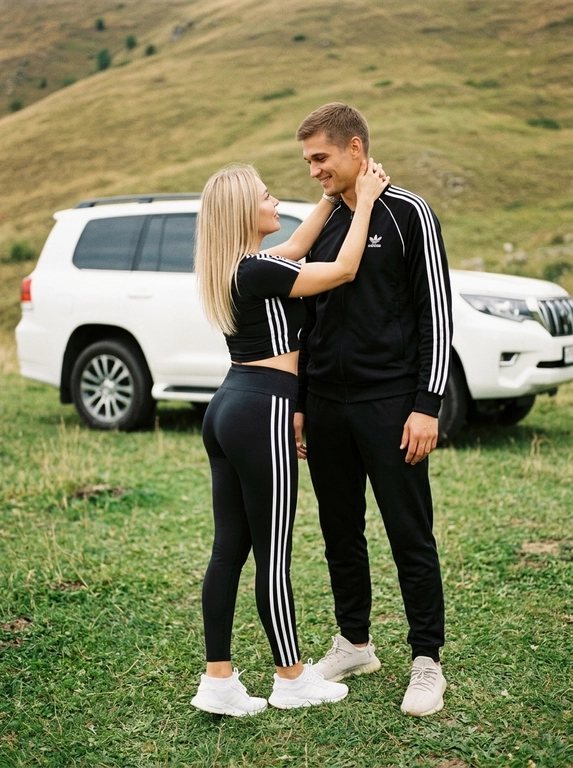 Пара у белого внедорожника на фоне зеленых холмов
