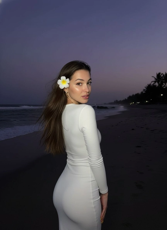 Сделай фото, будто я на пляже, где темно, но кто-то сфотографировал меня со вспышкой, и мое лицо немного блестит и светится, заднем плане закат, как будто солнце село на 98%, оставив фиолетовый оттенок, и само по себе почти темно. Фото сделано из-за моей спины, как будто  мне сказали, повернуться. Я в белом облегающем платье с цветком, заправленным в волосы. Волосы должны развеваться так, как будто дует слегка ветер.
