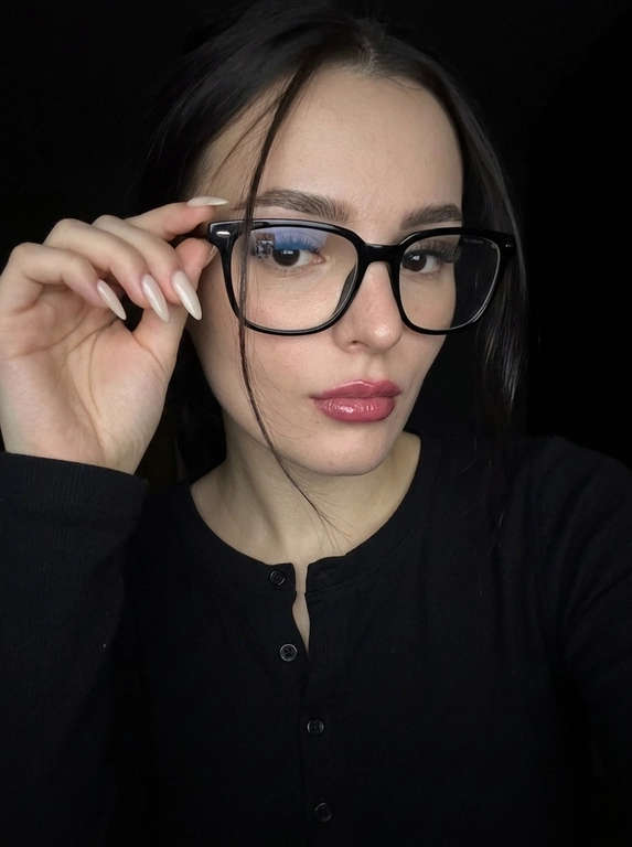 Максимально реалистичная фотография, темная винтажная эстетика в стиле dark glam glasses selfie, атмосферный ночной портрет.
Крупный портрет (Close-Up Portrait), кадр по грудь. Модель делает селфи, телефон не видно. Лицо занимает большую часть кадра, слегка повернуто вполоборота к камере. Голова немного наклонена. Взгляд направлен прямо в объектив, выражение спокойное, уверенное и притягательное. Губы слегка приоткрыты. Одна рука поднята к лицу и аккуратно касается оправы очков, словно поправляя их.
Макияж: Безупречный dark glam makeup. Ровный сияющий тон кожи, четко оформленные темные брови, длинные густые ресницы, тонкая стрелка, мягкий контуринг. Губы розово-винного оттенка с влажным глянцевым финишем.


Аксессуары: Крупные черные очки с прозрачными линзами и массивной квадратной оправой. На линзах заметны мягкие отражения света. Маленькие серьги-гвоздики. Длинный миндалевидный маникюр молочно-бежевого оттенка.

Одежда: Черный лонгслив с глубоким вырезом и небольшими пуговицами спереди. Темная ткань почти сливается с фоном, сохраняя видимую текстуру и силуэт.

Локация: Фон полностью черный.

Освещение: Мягкий приглушенный свет спереди и немного сбоку, словно от экрана телефона. Свет деликатно подсвечивает лицо, очки, губы, пальцы и ногти, оставляя волосы и одежду в глубоких тенях.

Камера: Реалистичное селфи высокого качества, RAW photo, натуральная перспектива смартфона, высокая детализация лица и аксессуаров.

Глубина резкости: Небольшая. Лицо, очки, губы и рука находятся в фокусе, фон растворяется в мягкой темноте.

Кожа: Реалистичная текстура кожи с видимыми порами, естественными переходами света и тени, без эффекта пластика и чрезмерной ретуши.

Детали: Блики на линзах очков, влажный блеск губ, отдельные волоски и пряди на лице, текстура ткани, отражения света на ногтях, легкое пленочное зерно.

Атмосфера: Загадочный ночной вайб, уверенность, женственность, винтажная эстетика, ощущение случайного красивого селфи в темноте.

Какая будет прическа?: Волосы перекинуты на одну сторону. Несколько тонких прядей проходят через щеку и губы, создавая живой эффект движения. Видна естественная текстура и мягкий блеск.
