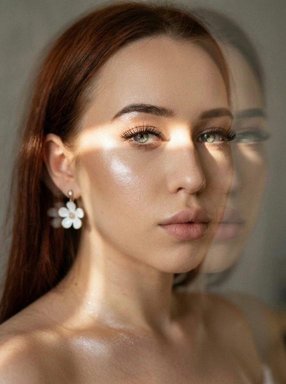 Кинематографический эффект с добавлением зерна. Ультрареалистичный, экстремально крупный портрет части лица девушки: на неё падает солнечный свет полосой, освещая глаза; её голова немного повёрнута в сторону. Тело подсвечено хайлайтером. Макияж лёгкий, с насыщенным хайлайтером; ресницы длинные, пышные. Она смотрит в камеру со спокойным, созерцательным выражением. Освещение мягкое, с лёгким акцентом на её лицо, создаёт нежные тени и подчёркивает черты. В ушах — серьги в виде белых цветов. Фон минималистичный и нейтральный, что усиливает спокойную и элегантную атмосферу. Фото смазанное, как будто сделано в движении, с двойной экспозицией.


Какая будет прическа?: Не изменять мою прическу.