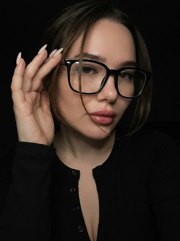 Максимально реалистичная фотография, темная винтажная эстетика в стиле dark glam glasses selfie, атмосферный ночной портрет.
Крупный портрет (Close-Up Portrait), кадр по грудь. Модель делает селфи, телефон не видно. Лицо занимает большую часть кадра, слегка повернуто вполоборота к камере. Голова немного наклонена. Взгляд направлен прямо в объектив, выражение спокойное, уверенное и притягательное. Губы слегка приоткрыты. Одна рука поднята к лицу и аккуратно касается оправы очков, словно поправляя их.
Макияж: Безупречный dark glam makeup. Ровный сияющий тон кожи, четко оформленные темные брови, длинные густые ресницы, тонкая стрелка, мягкий контуринг. Губы розово-винного оттенка с влажным глянцевым финишем.


Аксессуары: Крупные черные очки с прозрачными линзами и массивной квадратной оправой. На линзах заметны мягкие отражения света. Маленькие серьги-гвоздики. Длинный миндалевидный маникюр молочно-бежевого оттенка.

Одежда: Черный лонгслив с глубоким вырезом и небольшими пуговицами спереди. Темная ткань почти сливается с фоном, сохраняя видимую текстуру и силуэт.

Локация: Фон полностью черный.

Освещение: Мягкий приглушенный свет спереди и немного сбоку, словно от экрана телефона. Свет деликатно подсвечивает лицо, очки, губы, пальцы и ногти, оставляя волосы и одежду в глубоких тенях.

Камера: Реалистичное селфи высокого качества, RAW photo, натуральная перспектива смартфона, высокая детализация лица и аксессуаров.

Глубина резкости: Небольшая. Лицо, очки, губы и рука находятся в фокусе, фон растворяется в мягкой темноте.

Кожа: Реалистичная текстура кожи с видимыми порами, естественными переходами света и тени, без эффекта пластика и чрезмерной ретуши.

Детали: Блики на линзах очков, влажный блеск губ, отдельные волоски и пряди на лице, текстура ткани, отражения света на ногтях, легкое пленочное зерно.

Атмосфера: Загадочный ночной вайб, уверенность, женственность, винтажная эстетика, ощущение случайного красивого селфи в темноте.

Какая будет прическа?: Волосы перекинуты на одну сторону. Несколько тонких прядей проходят через щеку и губы, создавая живой эффект движения. Видна естественная текстура и мягкий блеск.