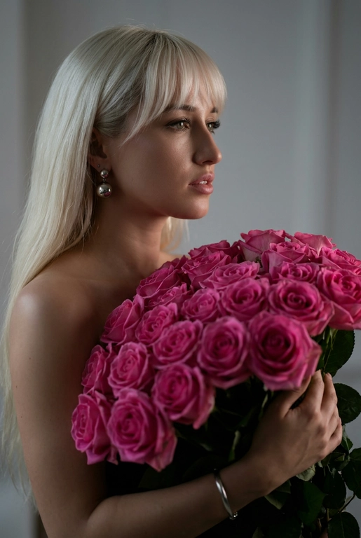 Создайте ультрареалистичный портрет, не меняя черты лица, крупным планом 3/4, с мягкой, освещённой кожей, атласной отделкой и естественным блеском, где женщина изображена в профиле. Спокойное и чувственное выражение лица, губы слегка полуоткрыты. Она носит серебряные серьги-шары и простой серебряный браслет на запястье.
Фон нейтральный, в светло-сером тоне, с тёмным, целенаправленным низким угловым освещением, которое подчёркивает контур лица, текстуру кожи и объём волос. Стиль редактирования — высокая мода, чёткий фокус 8K, реалистичная текстура, изысканная и элегантная атмосфера.


Такая же прическа как на оригинальном фото

Цветы: Держит в руках огромный букет розовых роз.