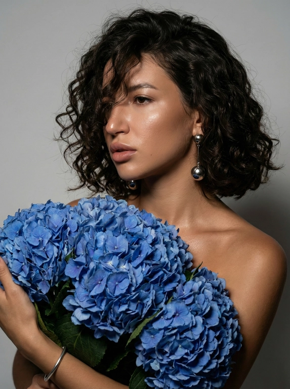   Создано с помощью сервиса Создать фото в режиме PRO

Промпт пользователя:
Создайте ультрареалистичный портрет, не меняя черты лица.  крупным планом 3/4 с мягкой и освещенной загорелой кожей, атласной отделкой и естественным блеском, где женщина в профиле . Волосы выше плеч карэ, которые покрывают хорошую часть лица с локонами, выпадающими на лицо и плечо.Цвет волос не меняй. Спокойное и чувственное выражение лица, а губы слегка полуоткрыты. Она носит серебряные серьги-шары и простой серебряный браслет на запястье. держит в руках огромный букет голубых гортензий. Фон нейтральный в светло-сером тоне, с темным и целенаправленным низким угловым освещением, которое улучшает контур лица, контур кожи и объем волос. Стиль редактирования красоты высокой моды, четкий фокус 8K, реалистичная текстура
изысканная и элегантная атмосфера.

