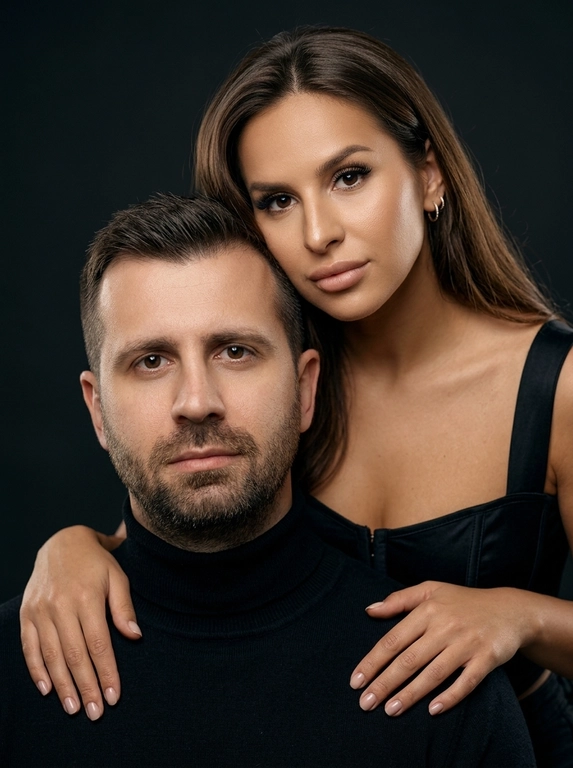 Гиперреалистичный студийный fashion-портрет молодой пары по загруженному референсу, 100% сходство лиц. Черты лица не изменять. Крупный план, кадр по плечи.
Мужчина, спокойный уверенный взгляд прямо в камеру, естественное выражение лица, одет в черный трикотажный свитер с высоким воротом.
Женщина с волосами цветом и длиной как на фото, мягкая боковая укладка. Она стоит позади мужчины и нежно обнимает его, ее руки лежат на его плечах. Ее лицо расположено рядом с его лицом, она повернута слегка боком, голова немного наклонена вперед, взгляд направлен прямо в камеру.
У женщины выразительные глаза с длинными густыми черными ресницами, естественный clean-glam макияж, натуральные брови, нюдовые губы, теплый оливковый оттенок кожи, небольшие серьги-кольца.
Композиция плотная и интимная, их лица расположены очень близко друг к другу, современный модный портрет пары. Девушка одета в черный корсет 
Кожа максимально натуральная: живая текстура кожи, видимые микропоры, subtle skin glow, естественный мягкий блеск кожи, natural skin microtexture, skin translucency, micro skin details, легкие естественные несовершенства кожи, без ретуши и без эффекта пластика.
Освещение: мягкий студийный beauty lighting, рассеянный ключевой свет спереди и немного сбоку, мягкие глубокие тени для объема лица, деликатные световые блики на коже.
Фон: глубокий темный студийный фон, темно-графитовый или почти черный, создающий контраст с кожей и лицами.
Стиль: luxury fashion editorial photography, high fashion portrait, ultra photorealistic, 85mm portrait lens, shallow depth of field, creamy bokeh, cinematic soft lighting, RAW photo, extremely detailed, fine hair strands, natural skin pores, professional photography, photorealism, 8k, high dynamic range.
Вертикальный формат 9:16
Негативный промт:
ai plastic skin, wax skin, overly smooth skin, doll face, beauty filter, cgi, 3d render, overretouched skin, unrealistic skin texture, bad anatomy, distorted face, extra fingers, low detail, blurry skin, artificial texture, oversharpen, fake lighting