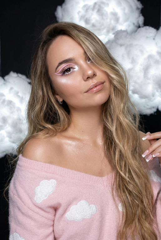 Крупный план лица девушки в стиле «высокой моды». Элегантный макияж глаза с длинными острыми нежно розовые двойные изогнутые стрелки, длинные густые ресницы эффект лучики, нижние густо ресницы накрашены белым и белый каял карандаш на нижнем веке белый Хайлайтер во внутренних уголках и скулах. Губы слегка приоткрыты в легкой ухмылке в легком блеске. Голова наклонена в сторону. На ней пушистый дорогой кашемировый нежно розовый свитер с белыми облаками плечи открыты.
За ней свисают объемные пушистые облака из ваты подсвеченные белым изнутри. Тело и декольте подсвечены хайлайтером и шиммером. Высокая детализация текстур кожи, одежды и волос. Черты лица-полностью сохранены как на референсном фото.
Ногти френч квадрат длинные.
На фоне светлая большая бьюти студия, вокруг темно, ее лицо освещено яркой лампой.  Волосы очень длинные блестящие прическа пляжные локоны. Локон волос падает на лицо 
