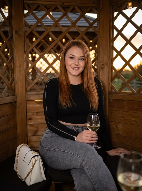 Портрет молодой красивой девушки с длинными прямыми волосами, позирующей внутри деревянной беседки в вечернее время. Она одета в облегающий черный кроп-топ с длинными рукавами на молнии и серые джинсы с высокой талией. Девушка сидит на деревянной скамье, поджав одну ногу, и держит в руке бокал с напитком. Рядом с ней стоит стильная белая кожаная сумка с золотой цепочкой. Освещение мягкое, сфокусированное на лице и фигуре, создающее эффект вспышки на фоне текстурированной деревянной решетки беседки. Реалистичное фото, высокое разрешение, детализация текстуры ткани и волос.