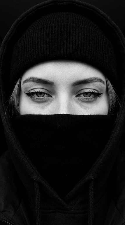 Не меняя внешности женщины с фото, перед нами крупный план её лица, частично скрытого под чёрной шапкой-бини, капюшоном и чёрной курткой с высоким воротом, которые обнимают нижнюю часть лица, оставляя видимыми только выразительные глаза.

Очень близкое селфи на iPhone 16, горизонтальный кадр, видно только глаза и брови, взгляд направлен прямо в камеру. Фото цветное, сильно затемнённое, с глубокими тенями, мягким контрастом и холодной приглушённой цветокоррекцией. Чёрные элементы одежды остаются насыщенными и глубокими, кожа сохраняет естественный оттенок без пересветов и искусственного сглаживания.

Веки полуприкрыты, создавая томный, тяжёлый и дерзкий взгляд. Стрелки большие, острые, дерзкие, с чёткими графичными линиями. Ресницы длинные и пушистые. Брови строго очерчены и подчеркнуты тёмным оттенком. Взгляд направлен прямо в камеру, создавая атмосферу загадочности и напряжённости.

Свет падает мягко и равномерно, но остаётся очень приглушённым, делая главный акцент на глубине взгляда. Волосы, видимые лишь частично, слегка выбиваются из-под шапки.

Фон очень тёмный, приглушённый, с минимальным количеством цветовых деталей и без ярких отвлекающих оттенков. Общая цветовая гамма холодная, глубокая и кинематографичная, с лёгким уклоном в серо-графитовые и нейтральные тона.

Стиль кадра кинематографичный, с высокой глубиной теней, реалистичной текстурой кожи и ткани, без глянцевой ретуши, без эффекта пластика и без ИИ-сглаживания. Фотореалистичное изображение, высокая текстурная детализация, разрешение 8K. Фото снято на iPhone 16.


Фото в чёрно-белом или в цвете?: Стиль кадра чёрно-белый