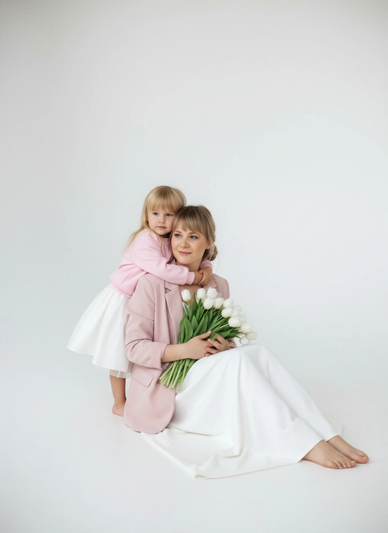 Объедини людей на фото. Не меняй внешность людей.
Женщина одета в белое платье в пол, босые ноги, розовый пиджак, в руках букет белых тюльпанов, волосы собраны в низкий пучек, лёгкий макияж. Девочка 4 лет одета в белую объемную юбочку которая слегка виднеется из под розового пиджака, босые ноги, волосы девочки распущены.
Женщина сидит на полу в белой циклораме, девочка слегка обнимает девочку
