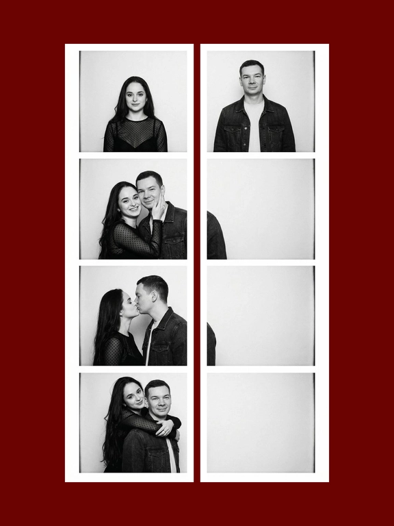 A black-and-white vertical vintage photobooth strip 1X4 of a man and a woman. The man wears a dark denim jacket over a light T-shirt. The woman wears a fitted semi-sheer black long-sleeve top with delicate small patterned details. Realistic candid couple energy, authentic photobooth snapshot feel, not too polished, not perfectly symmetrical, natural imperfect posing. All frames are stacked in a one column, one frame under another. Plain light studio background, strictly white photobooth borders with same width and square corners, realistic analog photobooth aesthetic, gentle film grain, soft contrast, natural skin texture, even frontal photobooth lighting. Frame 1: both stand side by side facing the camera, the woman on the left and the man on the right, slight height imbalance preserved, empty space between them, symmetrical centered composition. The woman's head slightly turned to the right, a flirtatious smile, a glance to the side. Frame 2: the woman turns toward the man and gently holds his cheek with one hand, smiling brightly; the man turns toward her with a soft smile. Their faces are close, but the composition remains off-center and slightly left-weighted, with more negative space on the right. Frame 3: the couple kiss in profile, the woman on the left and the man on the right, the couple is positioned close to the left side of the frame, extra empty space on the right side. The woman on his left, her hand on the men's cheek. Frame 4: the woman hugs the man from behind over his shoulders, her head leaning from the upper left side toward him, while the man faces the camera smiling. the couple is positioned very close to the left side of the frame, the right half of the frame is empty.
